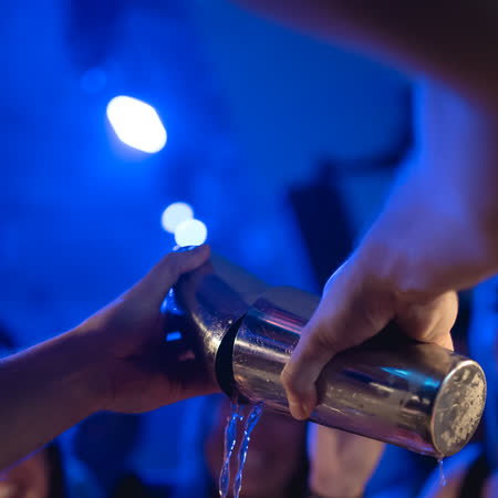Il barman versa un cocktail, i bicchieri pronti in fila