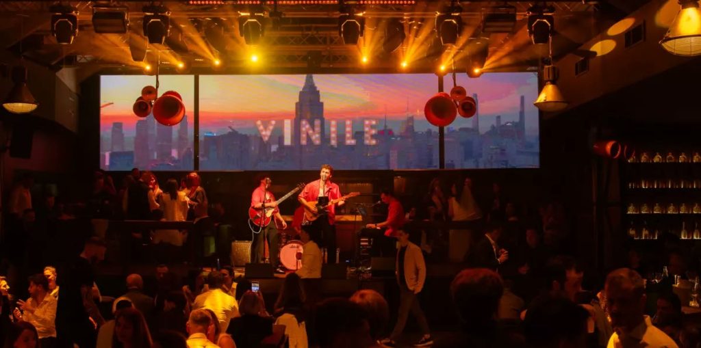 La band sul palco sotto l insegna VINILE, il pubblico ai tavoli